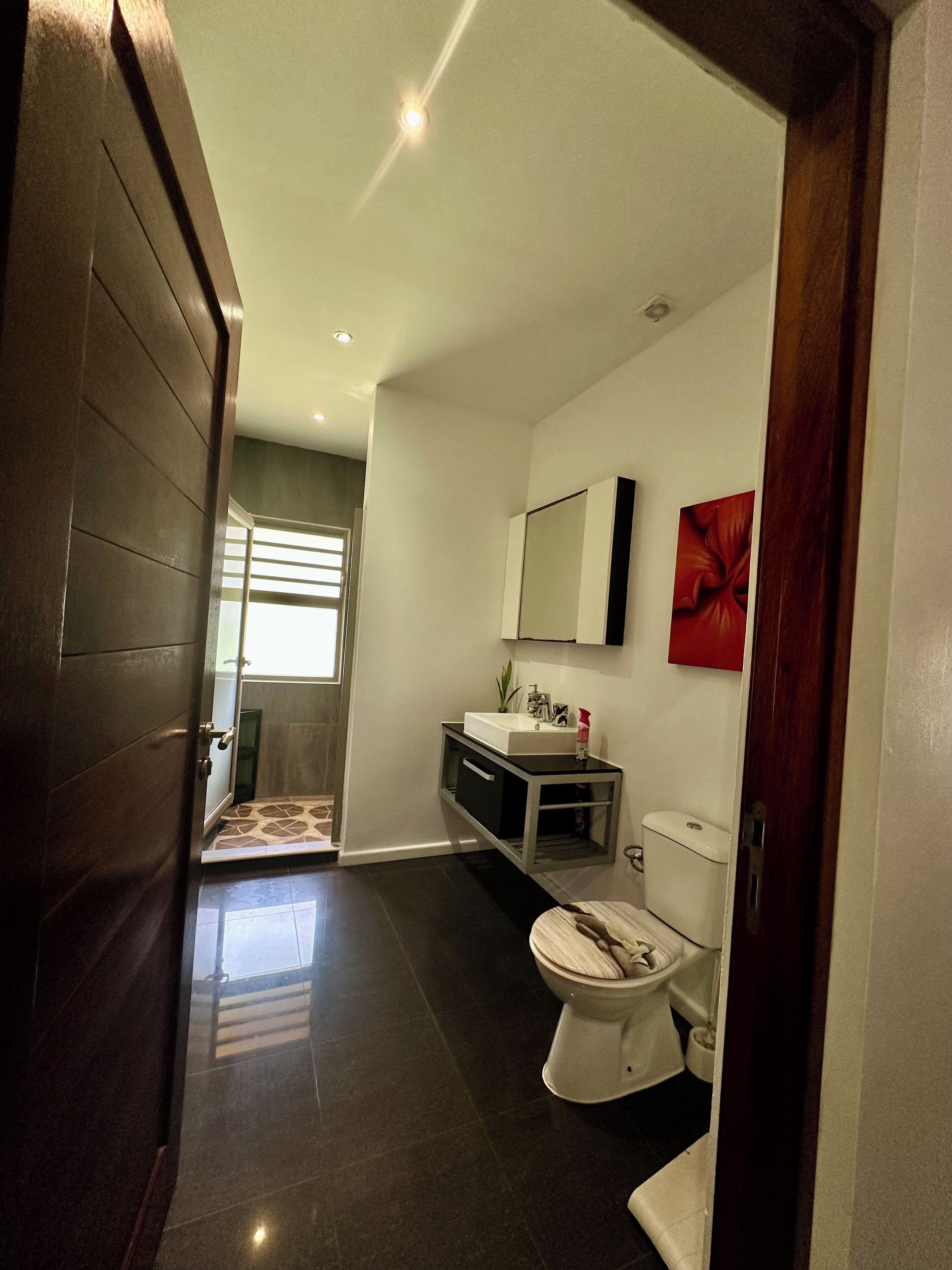 A modern bathroom with a toilet, sink, and mirror.