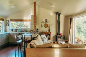 Una sala acogedora con sofá, una mesa de comedor y una cocina con estufa.