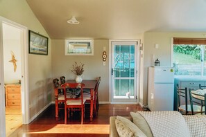 A dining area with a wooden table and chairs, a vase with dried flowers, and a painting on the wall.