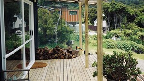 A wooden deck with a glass door leading to a lush garden.