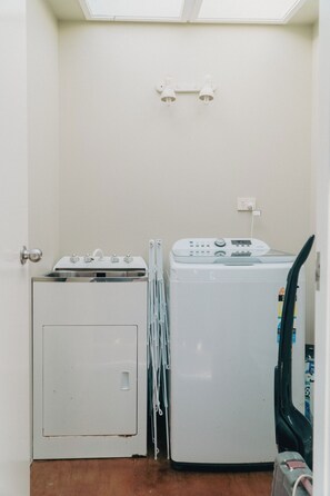 Een wasserette met een droger, een wasmachine en een klein kastje.
