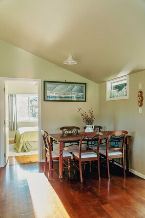 Un comedor con mesa y sillas de madera, un cuadro en la pared y una ventana con cortinas.