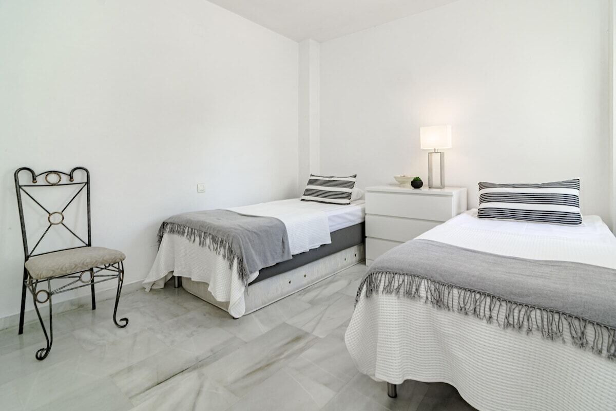 Ein Schlafzimmer mit zwei Betten, einem Nachttisch, einem Sessel und einer Lampe.