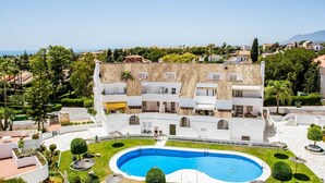 Ein modernes Hotel mit Dachpool, umgeben von üppiger Vegetation und freiem Blick auf das Meer.