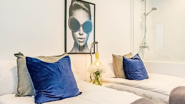 Een hotelkamer met een bed, een douche en een kunstwerk in een lijst aan de muur.