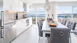 Eine moderne Küche mit weißen Schränken, einem Edelstahlkühlschrank und einem Essbereich mit Tisch und Stühlen.
