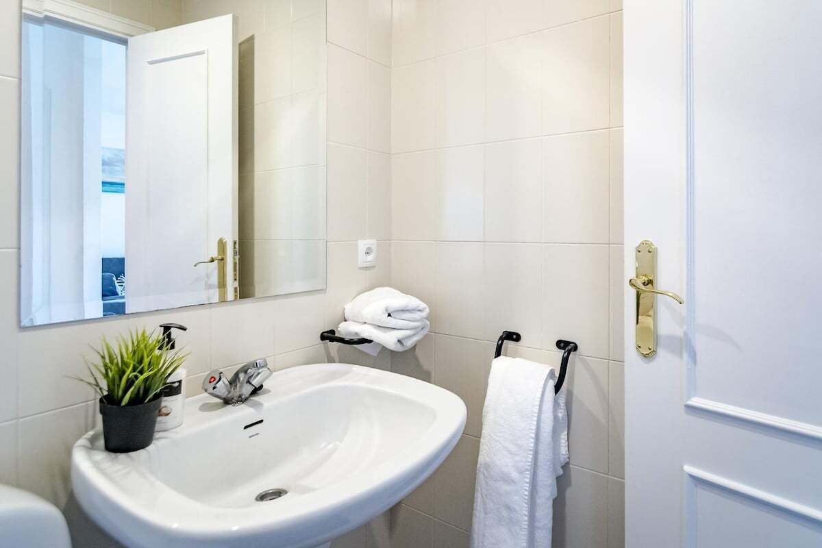 Een badkamer met een witte wasbak, een spiegel, een handdoekhouder en een toilet.