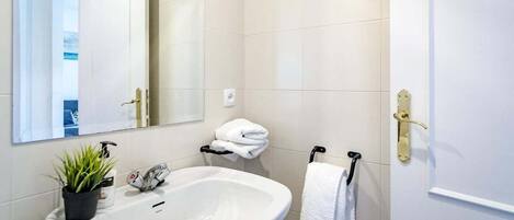 Een badkamer met een witte wasbak, een spiegel, een handdoekhouder en een toilet.