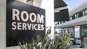 Un cartel que dice 'ROOM SERVICES' con un edificio moderno al fondo.