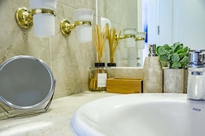 A bathroom with a round mirror, a white sink, and a marble countertop. There are wall-mounted lights and a small plant on the counter. - Saa2- Comfortable Apartment Puerto Banus (Marbella)