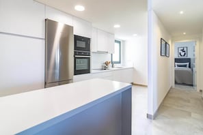 A modern kitchen with stainless steel appliances, white cabinetry, and a large island. - Inf3.6k - Luxury Apartment Perfect Location (Estepona)