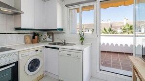 Una cucina compatta con lavatrice, lavastoviglie e lavello.