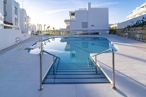 Ein moderner Poolbereich mit klarem, blauem Wasser, Metallgeländern und einer Steinmauer.