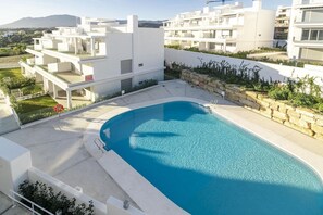 A modern residential building with a swimming pool, balconies, and a view of the surrounding landscape. - Lm12b- Exclusive 2 Bedroom Apartment in Le Mirage (Estepona)