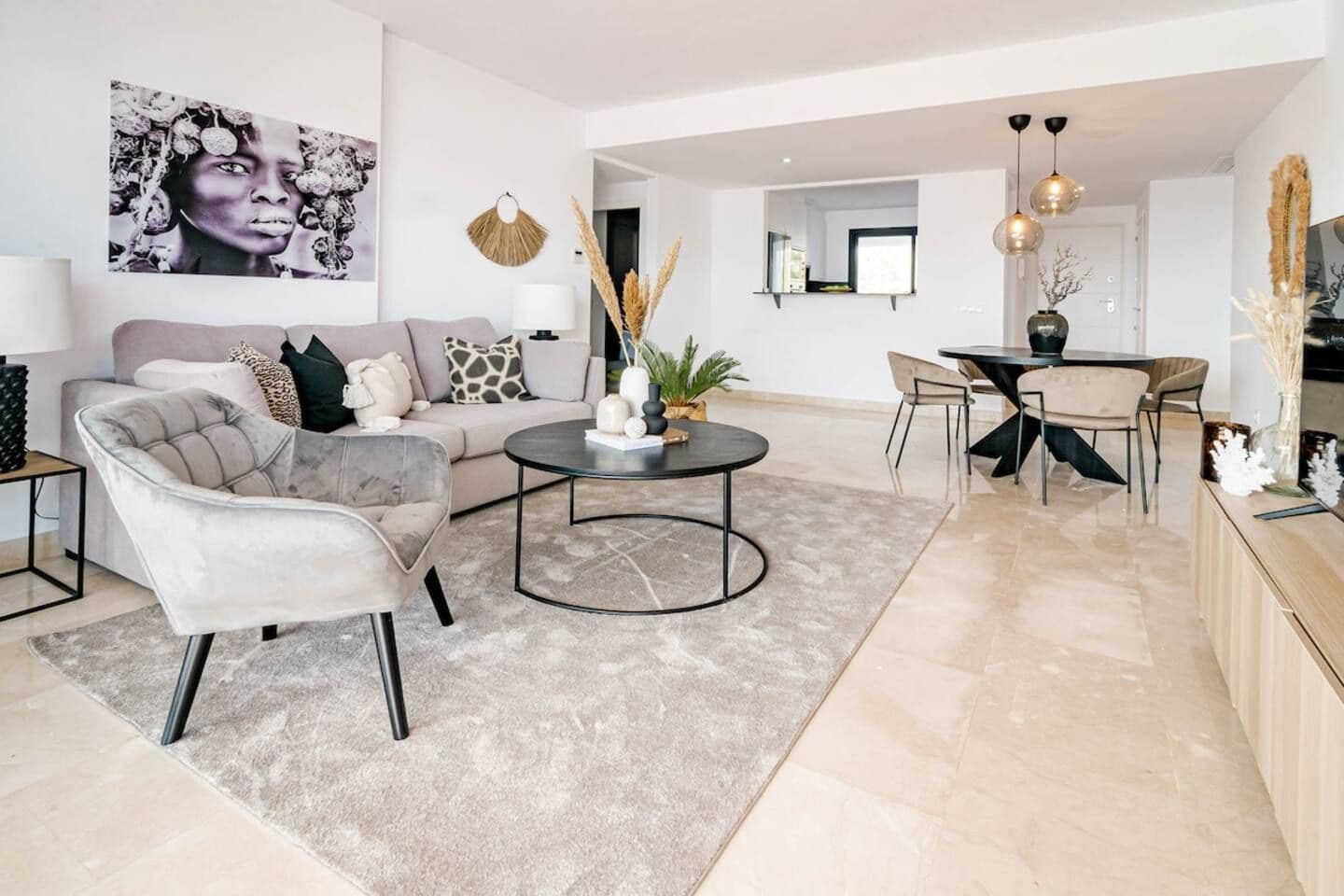 Ein modernes Wohnzimmer mit Sofa, Sessel, Couchtisch und Essbereich.