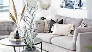 A modern living room with a round table, a grey sofa, and a decorative vase with branches. - Dja- Modern 2 Bedroom Apartment Close to Beach (Casares)