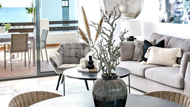 A modern living room with a round dining table, a sofa, and a view of the ocean. - Dja- Modern 2 Bedroom Apartment Close to Beach (Casares)