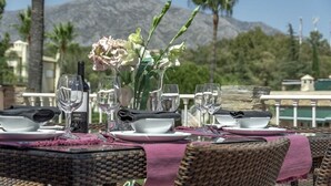 Une table dressée pour le dîner, avec vue sur une montagne et des palmiers.