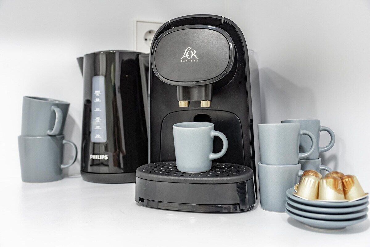 Una cafetera, una jarra de café Philips y varias tazas grises.