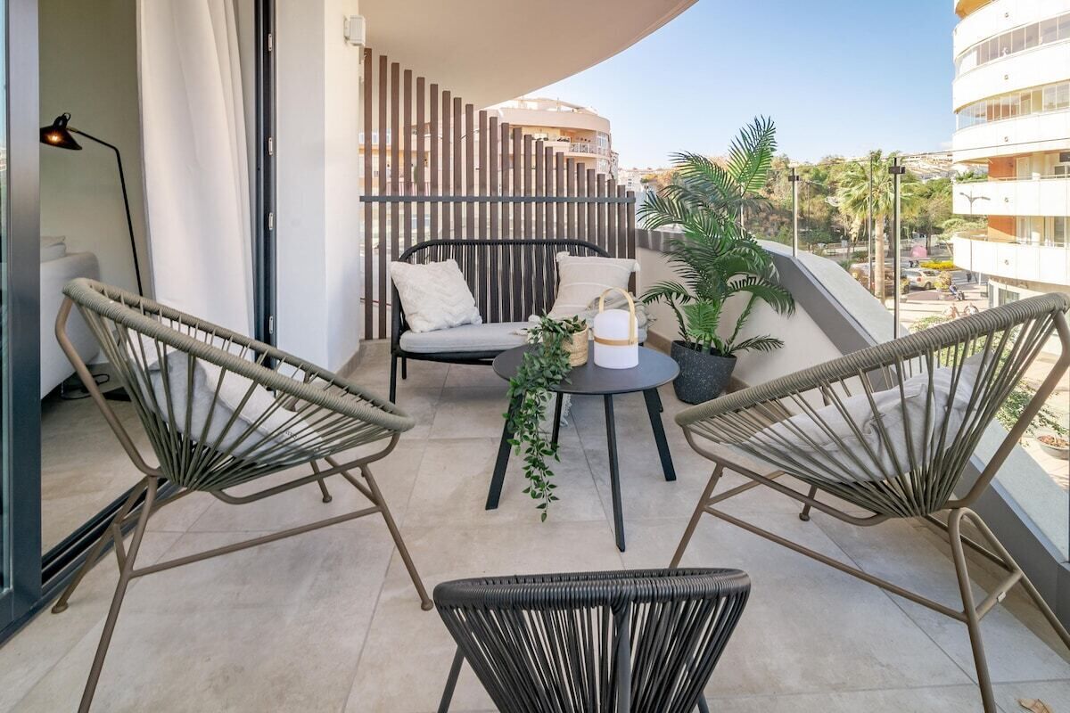 A balcony with wicker chairs, a small table with a plant, and a sofa.