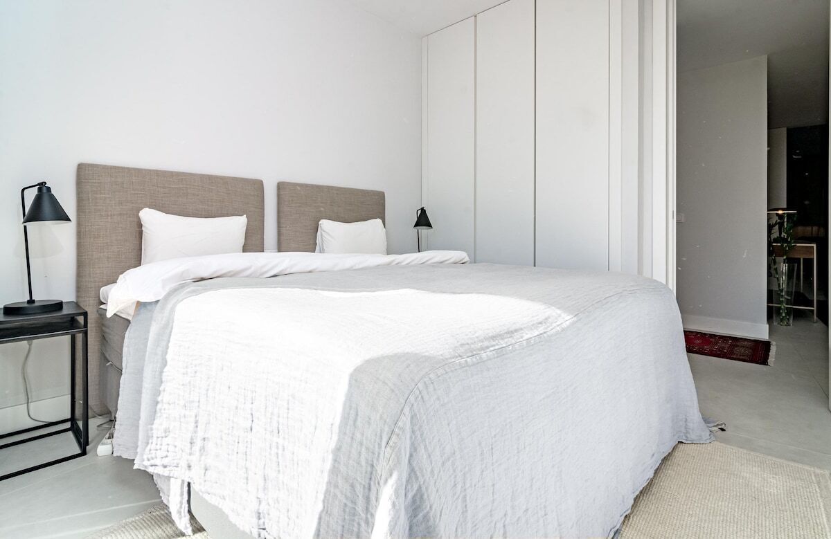 A modern bedroom with a large bed, two bedside tables, and a nightstand.