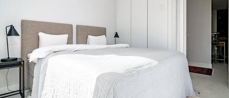 A modern bedroom with a large bed, two bedside tables, and a nightstand.