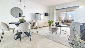 Een moderne woonkamer met een eetgedeelte, een flatscreen-tv en een groot raam met uitzicht op de stad.