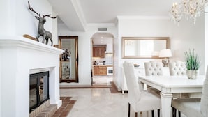 A dining area with a white table, chairs, and a chandelier. - Lap- 3 bed Apartment on the Beach. Families Only (Casares)