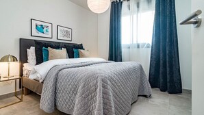 Une chambre moderne avec un grand lit, une table de chevet et une lampe fixée au mur.
