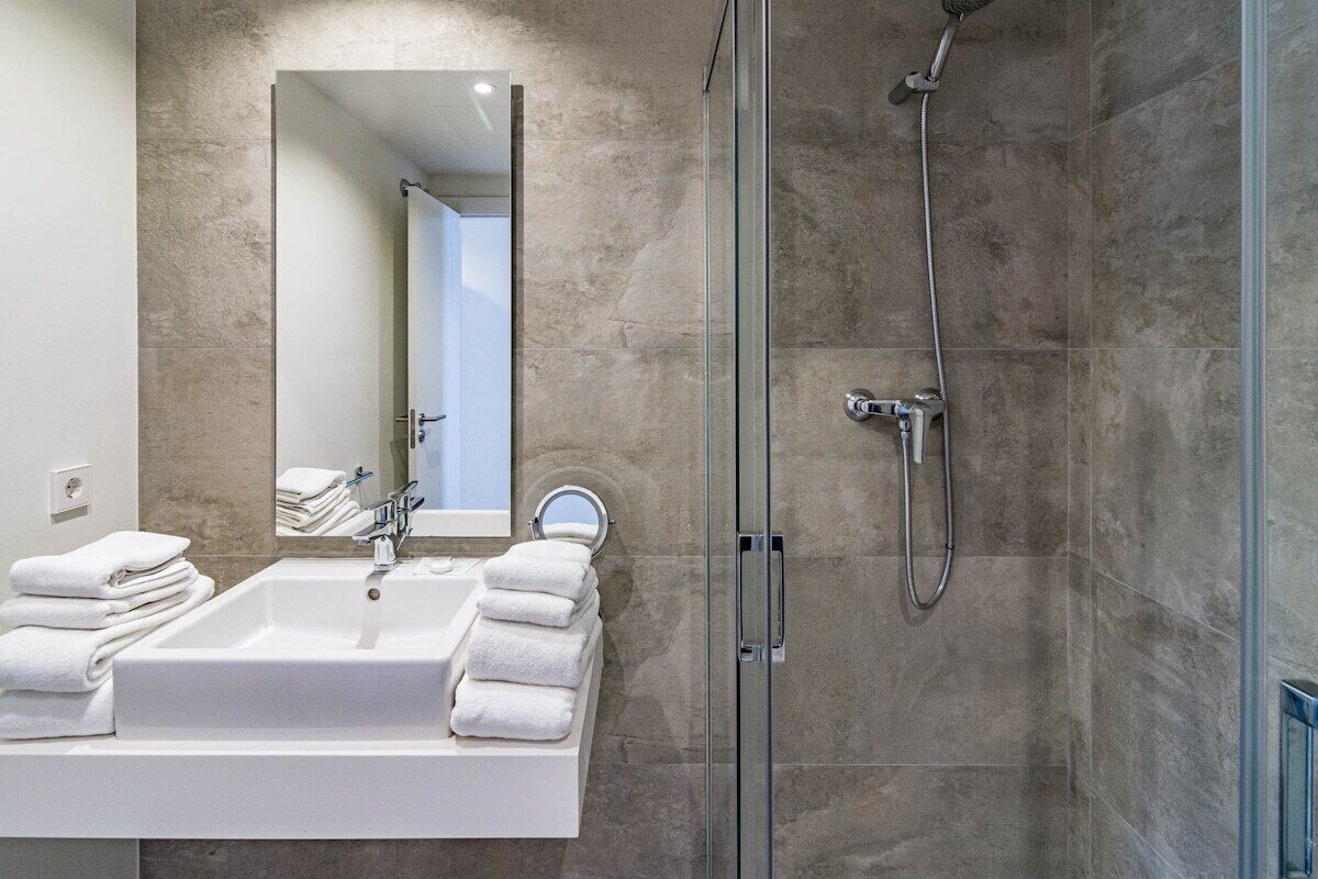 Une salle de bain moderne avec une douche à parois de verre, un lavabo blanc et un miroir.