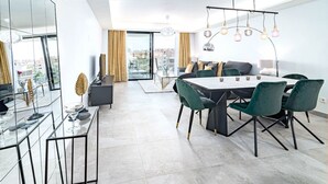 Un espace de restauration moderne doté d’une grande table et de chaises, d’une cloison en verre et offrant une vue sur la ville grâce à de grandes fenêtres.