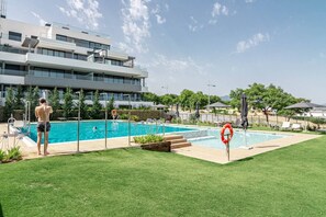 A swimming pool with a lifebuoy, a person in swimwear, and a modern building in the background. - Lme9f1- Penthouse, Amazing Views, Families Only (Estepona)