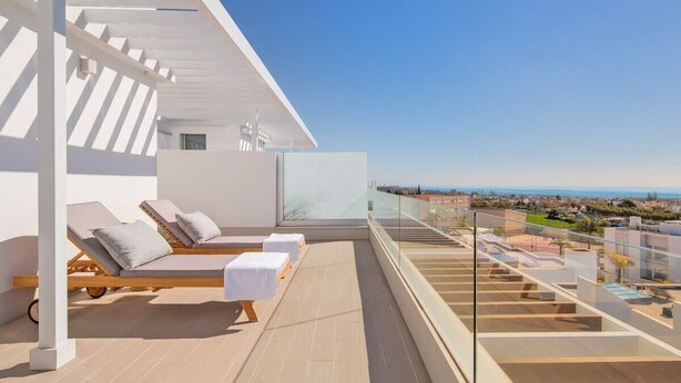 A rooftop terrace with sun loungers and a glass balustrade overlooking a cityscape. - Lm352b- Spacious Duplex Penthouse With Panoramic (Estepona)