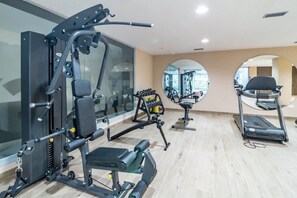 Un gimnasio con equipo de ejercicio, una cinta de correr y un espejo grande.
