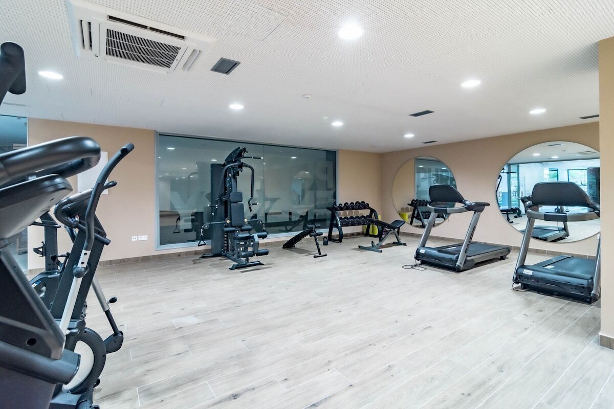 A gym with treadmills, weight machines, and a mirrored wall.