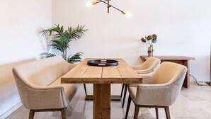 Un comedor con una mesa de madera y cuatro sillas, una lámpara colgante y una planta en maceta.