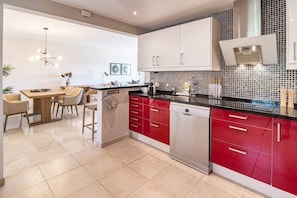 A modern kitchen with white and red cabinetry, a dishwasher, and a tiled backsplash. - Ma7b-stunning Holiday Home top Location (Marbella)