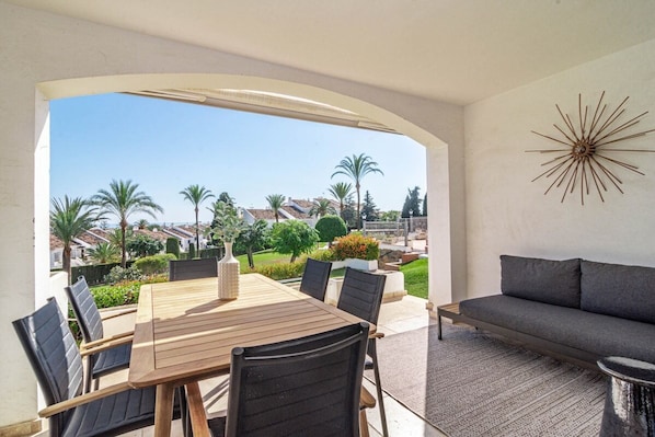 A patio with a wooden table and chairs, a gray sofa, and a decorative wall piece. - Ma7b-stunning Holiday Home top Location (Marbella)