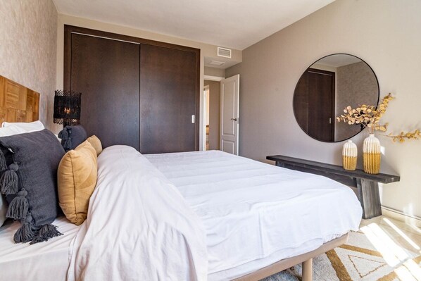 A bedroom with a large bed, dark wooden wardrobe, a round mirror, and a small table with decorative items. - Ma7b-stunning Holiday Home top Location (Marbella)