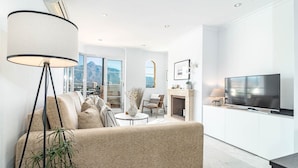 A modern living room with a sofa, a floor lamp, and a TV. - Sam24i- Cozy Apartment Walking Distance to Beach (Marbella)