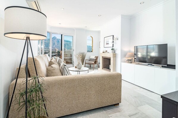 Ein modernes Wohnzimmer mit einer Couch, einer Stehlampe und einem Fernseher.