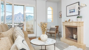 A spacious living room with a sofa, a round coffee table, and a fireplace. - Sam24i- Cozy Apartment Walking Distance to Beach (Marbella)