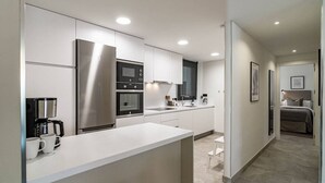 A modern kitchen with white cabinetry, stainless steel appliances, and a central island. - In33k- Stunning City Apartment Close to Beaches (Estepona)