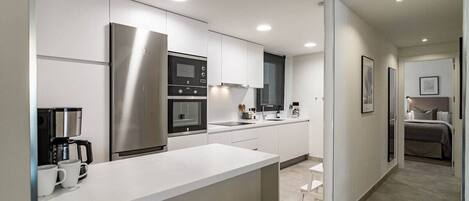 A modern kitchen with white cabinetry, stainless steel appliances, and a central island.