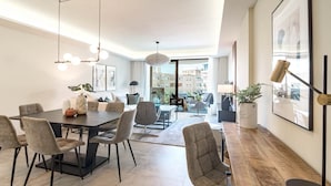 A modern living room with a dining area, large windows, and a view of the city. - In33k- Stunning City Apartment Close to Beaches (Estepona)