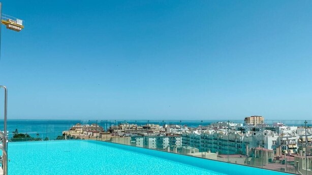 A rooftop infinity pool with a clear view of the cityscape and ocean. - In33k- Stunning City Apartment Close to Beaches (Estepona)