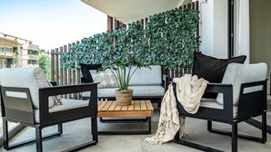 A modern outdoor seating area with two sofas, a wooden table, and a potted plant. - In33k- Stunning City Apartment Close to Beaches (Estepona)