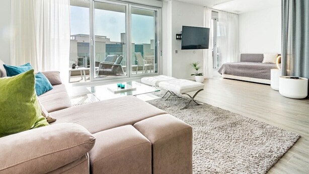 A modern living room with a sofa, coffee table, and a large sliding glass door leading to a balcony with outdoor furniture. - Lm111a- Modern Flat, Amazing Views (Estepona)