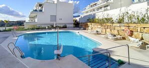 Una piscina con un flotador salvavidas, una silla de salvavidas y sillas de descanso.