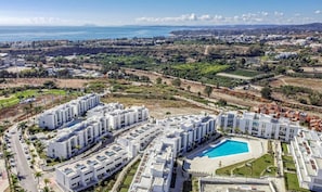 A coastal residential area with modern white buildings, a swimming pool, and a view of the sea. - Lm11.1a- Modern Flat, Amazing Views (Estepona)